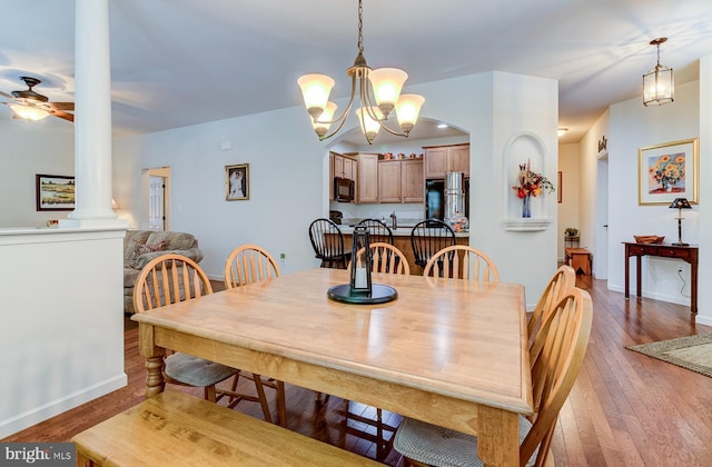 dining space featuring ceiling fan with notable chandelier, hardwood / wood-style flooring, and ornate columns