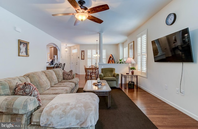 living room featuring wood-type flooring, ceiling fan with notable chandelier, and plenty of natural light