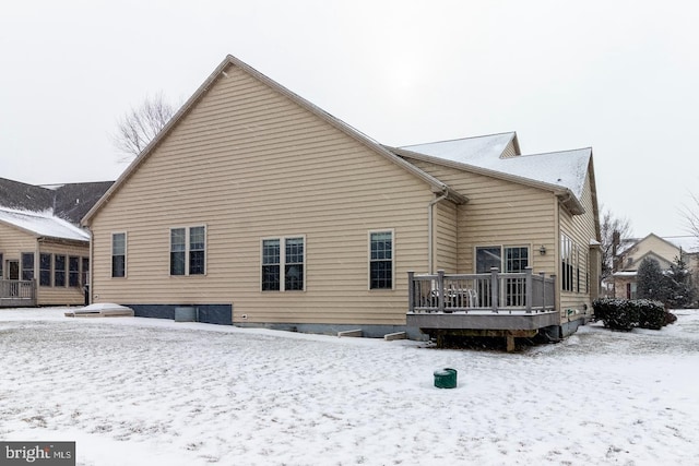 snow covered rear of property featuring a deck