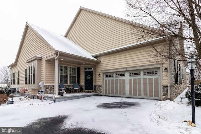 view of front of property with a garage, cooling unit, and a porch