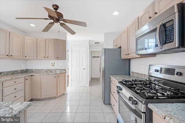 kitchen featuring light tile patterned flooring, ceiling fan, light brown cabinetry, light stone countertops, and appliances with stainless steel finishes