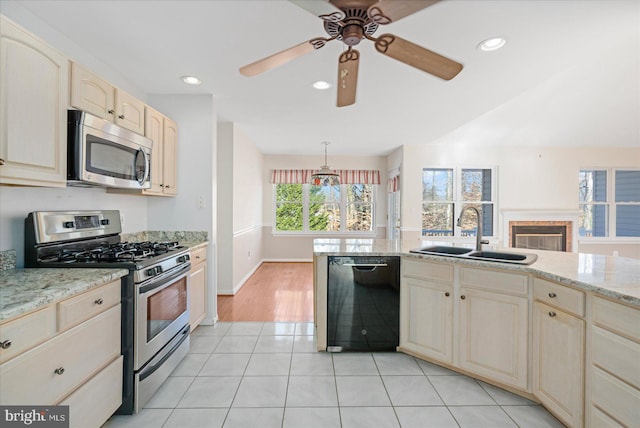 kitchen with stainless steel appliances, light stone countertops, light tile patterned floors, pendant lighting, and sink