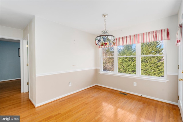 empty room featuring a notable chandelier and hardwood / wood-style flooring