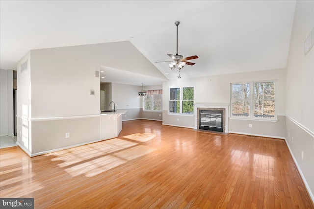 unfurnished living room featuring high vaulted ceiling, light wood-type flooring, ceiling fan, and sink