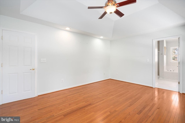 unfurnished room featuring ceiling fan, a tray ceiling, and wood-type flooring