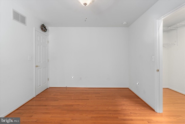 unfurnished bedroom featuring a walk in closet and light hardwood / wood-style floors