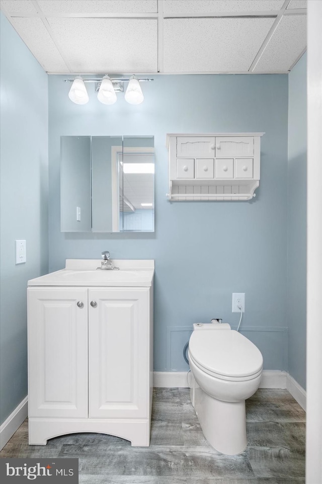 bathroom with a paneled ceiling, hardwood / wood-style floors, and toilet