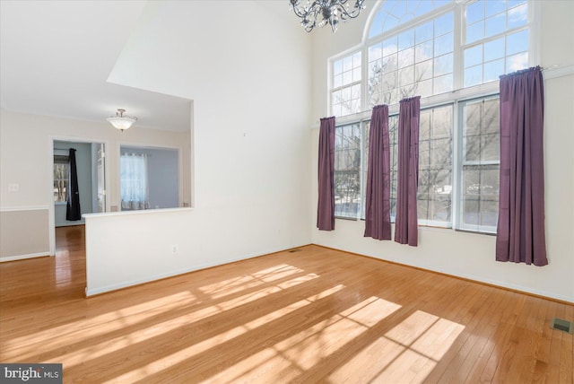 unfurnished room with a high ceiling, hardwood / wood-style flooring, and a chandelier