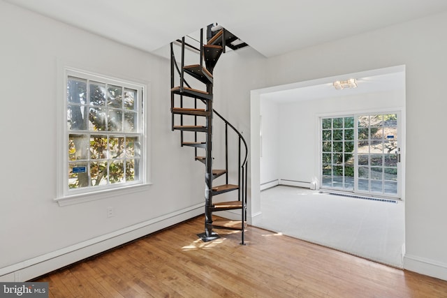 interior space featuring a baseboard heating unit, stairway, and wood finished floors