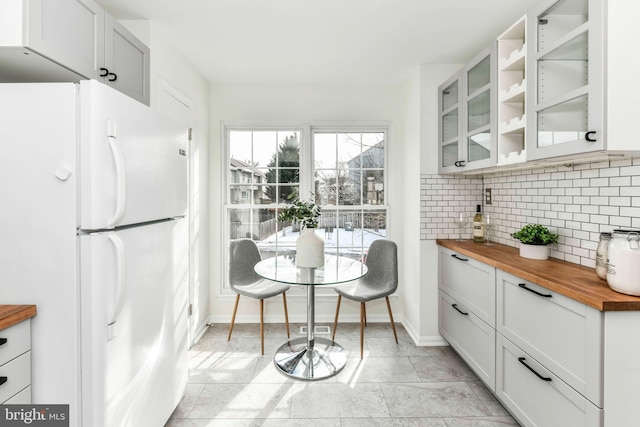 kitchen with white refrigerator, white cabinetry, and butcher block countertops