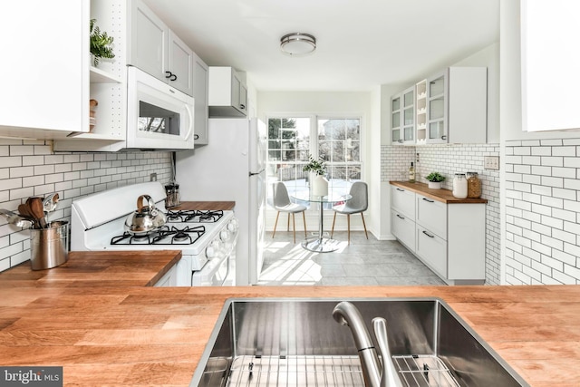 kitchen featuring white appliances, butcher block countertops, tasteful backsplash, and white cabinetry