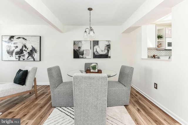 dining space with hardwood / wood-style flooring and a notable chandelier