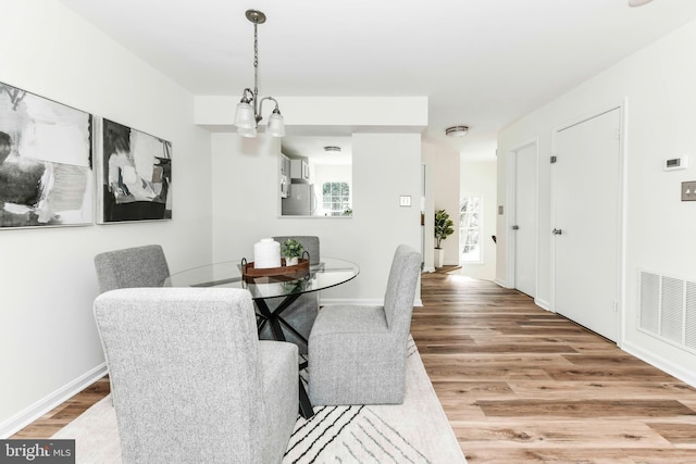 dining space with wood-type flooring and a notable chandelier