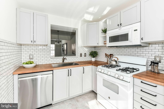 kitchen with white appliances, white cabinets, butcher block countertops, and sink