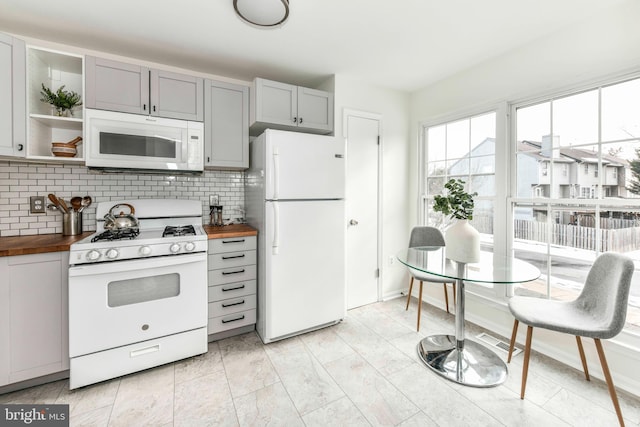 kitchen featuring white appliances, wooden counters, and tasteful backsplash