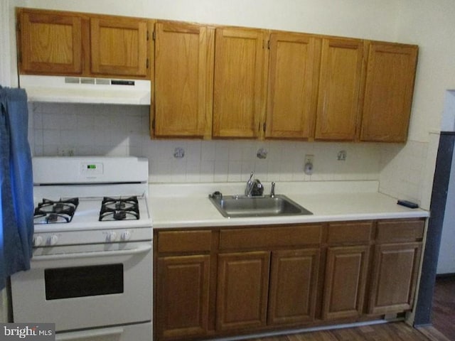 kitchen with backsplash, white gas stove, dark hardwood / wood-style floors, and sink