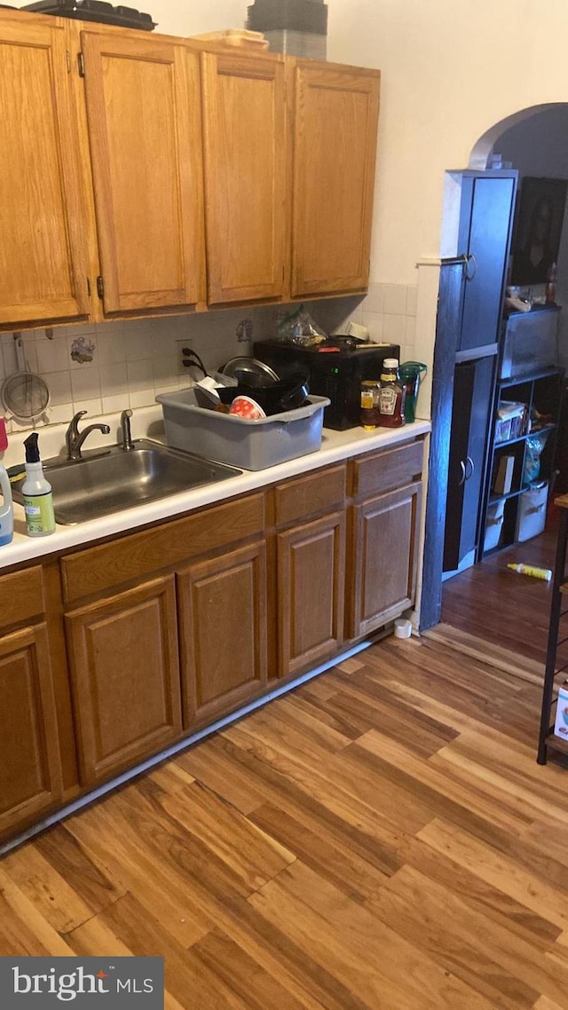 kitchen featuring decorative backsplash, sink, and wood-type flooring