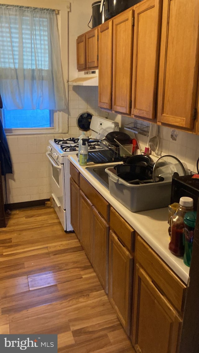 kitchen with white range with gas cooktop and light hardwood / wood-style flooring