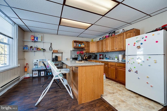 kitchen featuring a center island, tasteful backsplash, a kitchen breakfast bar, white refrigerator, and a paneled ceiling