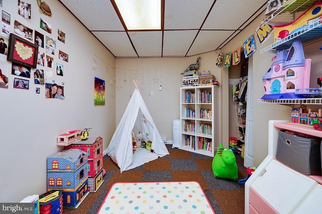 rec room with a paneled ceiling and dark colored carpet