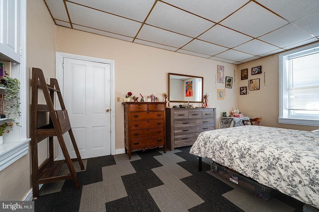 carpeted bedroom with a paneled ceiling and a closet