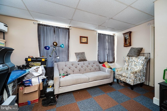 living room with a drop ceiling and a wall mounted AC