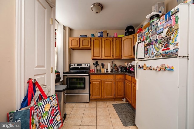 kitchen with white refrigerator, stainless steel electric range oven, and light tile patterned floors