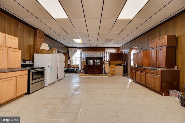 kitchen with wood walls, stainless steel electric range, and white refrigerator