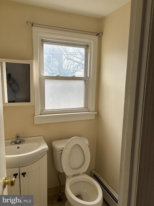 bathroom featuring toilet, a baseboard heating unit, and vanity