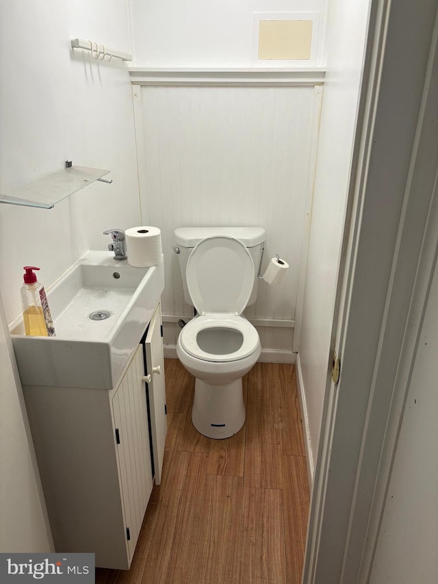 bathroom with toilet, vanity, and hardwood / wood-style floors