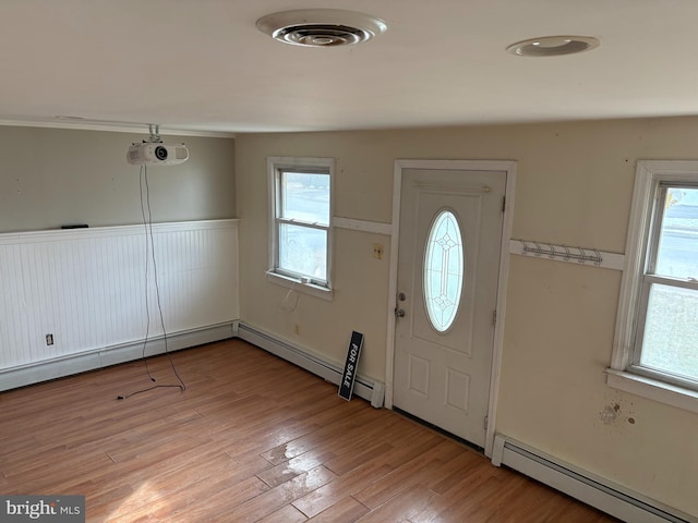 foyer entrance featuring a baseboard heating unit and light wood-type flooring