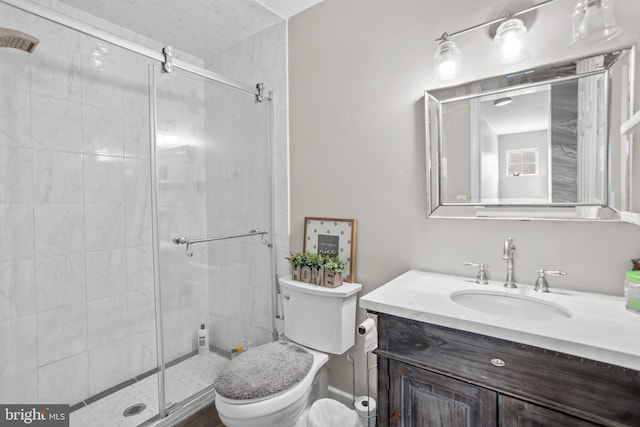 bathroom with toilet, vanity, and a shower with door