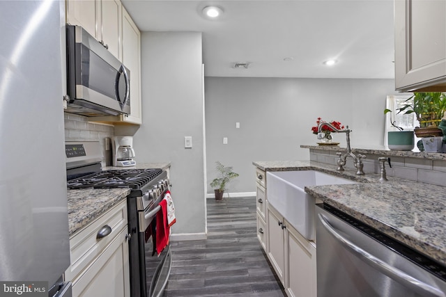 kitchen featuring light stone countertops, white cabinets, appliances with stainless steel finishes, and dark hardwood / wood-style flooring