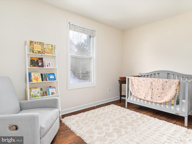 bedroom featuring a nursery area and dark wood-type flooring