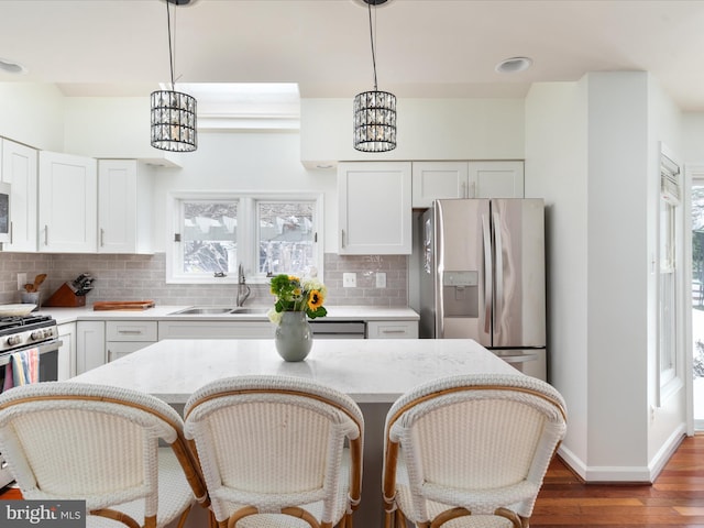 kitchen with sink, white cabinets, pendant lighting, and appliances with stainless steel finishes