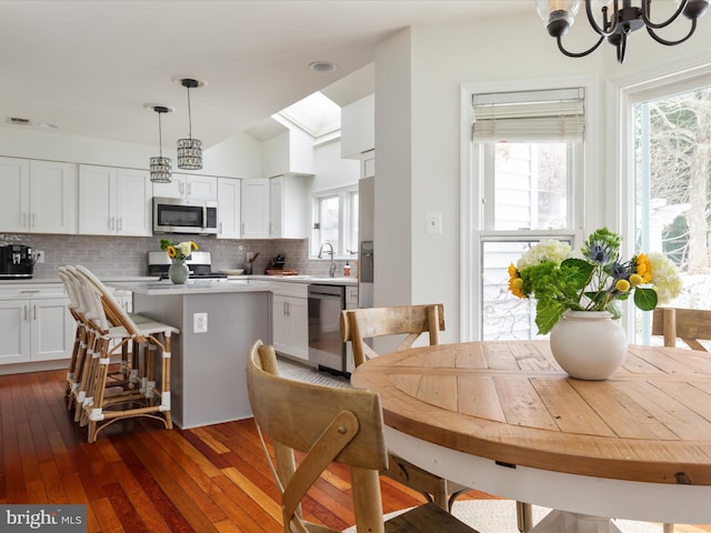 dining room featuring sink, dark wood-type flooring, and a chandelier