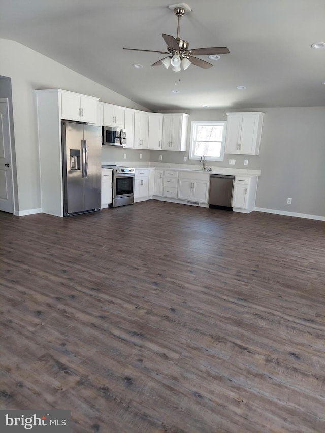 kitchen with appliances with stainless steel finishes, vaulted ceiling, dark wood-type flooring, sink, and white cabinets