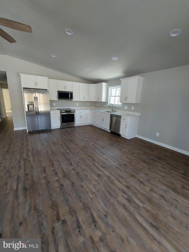 kitchen with stainless steel appliances, vaulted ceiling, sink, dark hardwood / wood-style floors, and white cabinetry