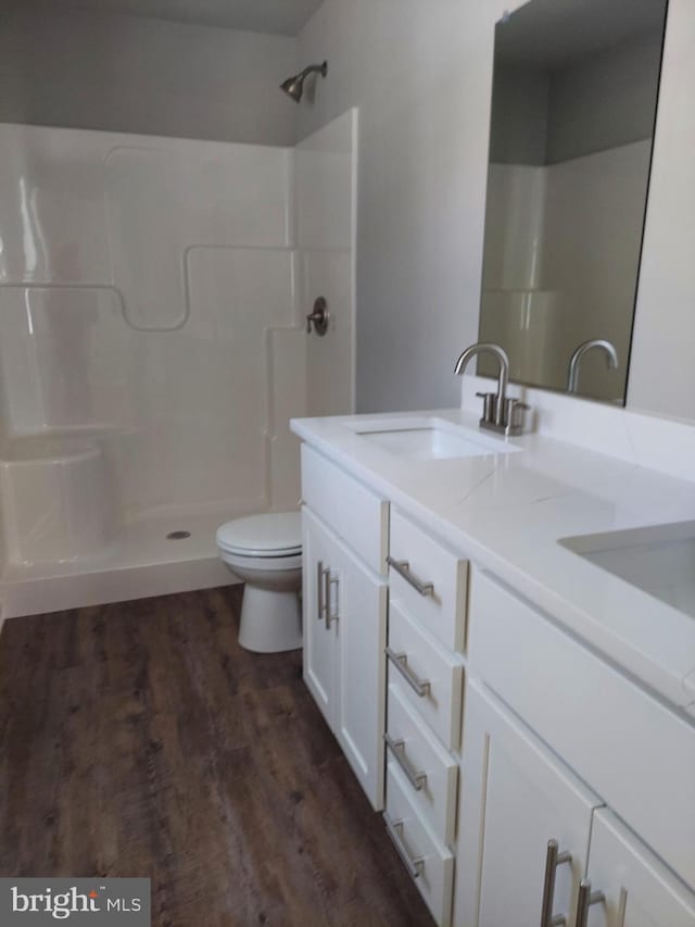 bathroom with a shower, vanity, hardwood / wood-style flooring, and toilet