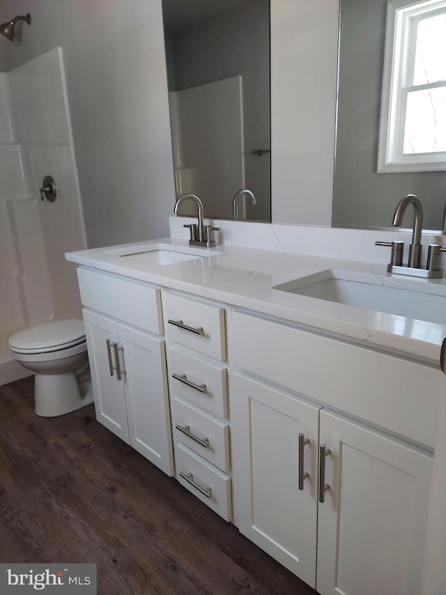 bathroom with hardwood / wood-style floors, vanity, toilet, and walk in shower