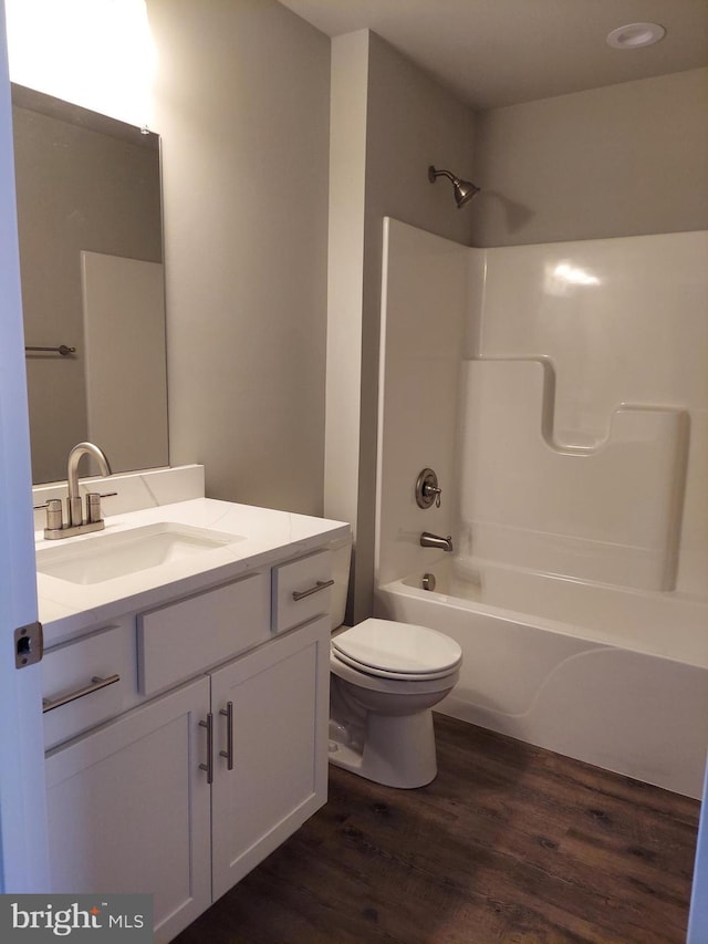 full bathroom featuring hardwood / wood-style floors, vanity, bathing tub / shower combination, and toilet