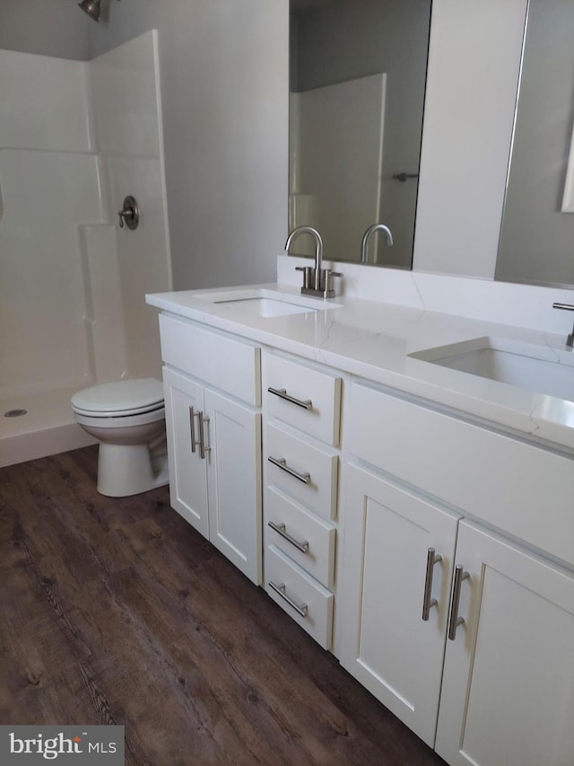 bathroom featuring hardwood / wood-style floors, vanity, toilet, and a shower