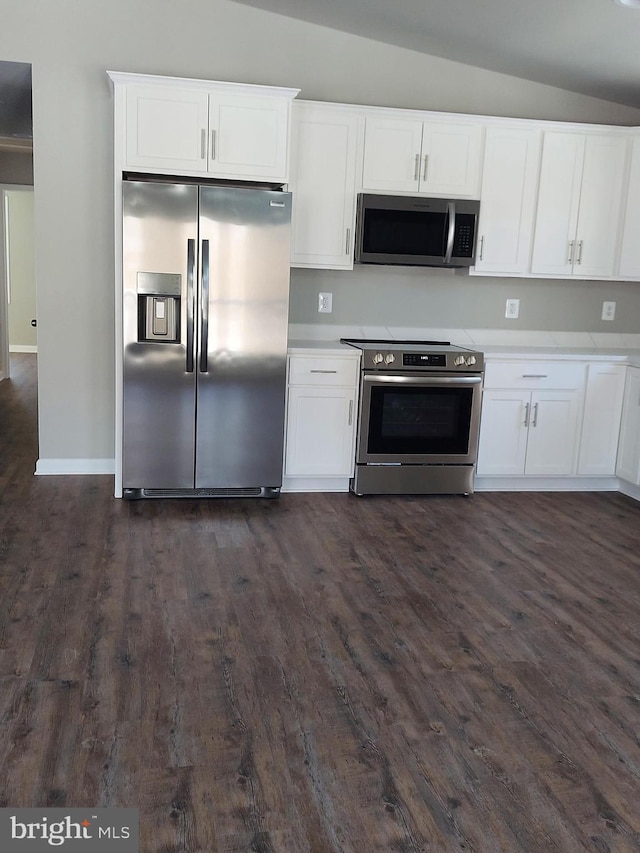 kitchen with white cabinetry, dark wood-type flooring, appliances with stainless steel finishes, and vaulted ceiling