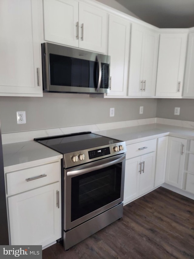 kitchen with white cabinets, stainless steel appliances, and dark wood-type flooring