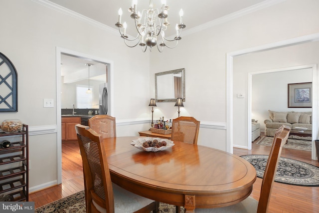 dining area featuring sink, crown molding, and light hardwood / wood-style floors