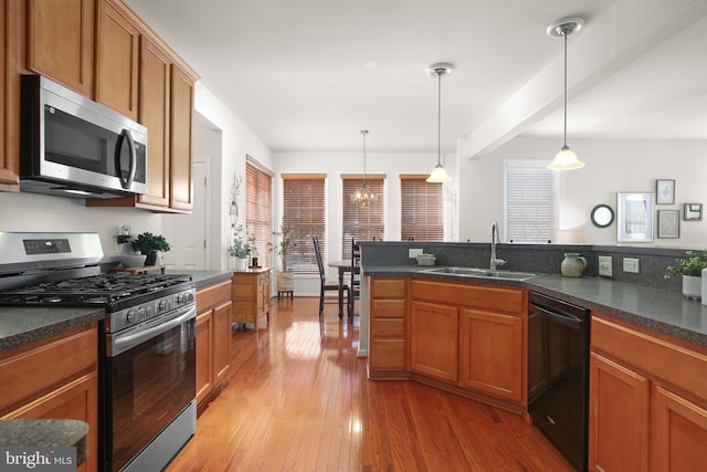 kitchen featuring appliances with stainless steel finishes, sink, pendant lighting, and light hardwood / wood-style flooring