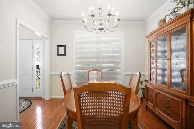 dining room with hardwood / wood-style flooring, ornamental molding, and a notable chandelier