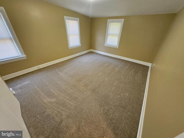 carpeted empty room with vaulted ceiling