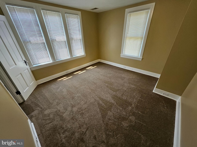 spare room featuring dark colored carpet