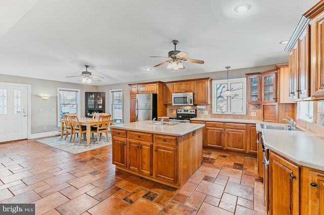 kitchen featuring a center island, sink, hanging light fixtures, a healthy amount of sunlight, and stainless steel appliances